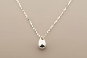 Silver teardrop pendant necklace on a gray background