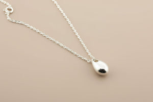 Silver teardrop pendant necklace on a gray background