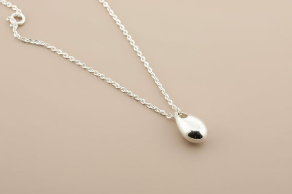 Silver teardrop pendant necklace on a gray background