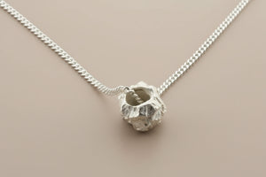 Silver necklace with a unique pendant on a gray background