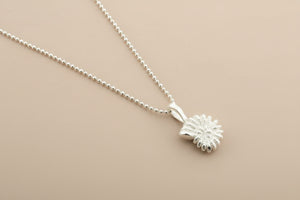 Silver necklace with a small round pendant on a gray background