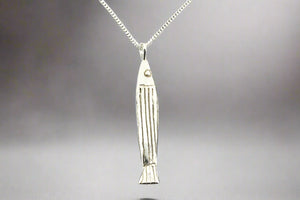 Silver fish-shaped pendant on a chain against a gray background