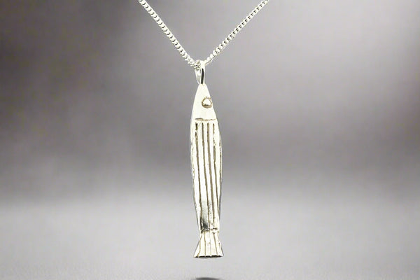 Silver fish-shaped pendant on a chain against a gray background