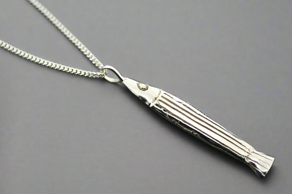 Silver tassel pendant on a chain against a dark background