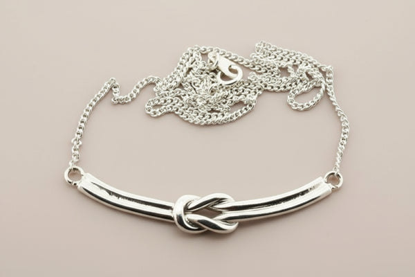 Silver bracelet with a knot design on a gray background