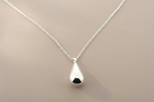 Silver teardrop pendant necklace on a gray background