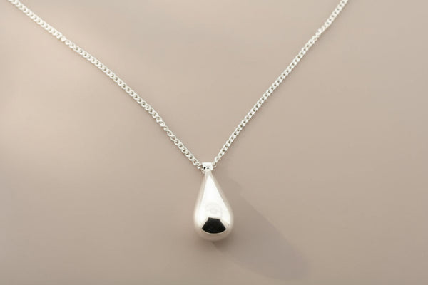 Silver teardrop pendant necklace on a gray background