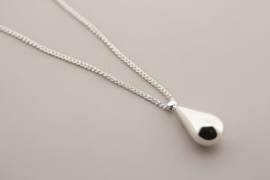 Silver necklace with a teardrop-shaped pendant on a gray background