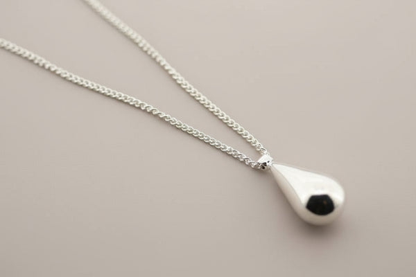 Silver necklace with a teardrop-shaped pendant on a gray background