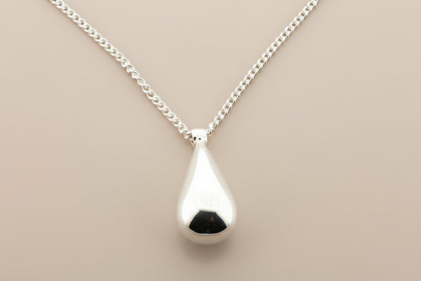Silver teardrop pendant necklace on a gray background