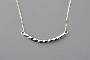 Silver necklace with a textured bar pendant on a gray background