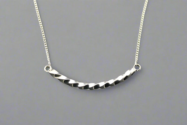 Silver necklace with a textured bar pendant on a gray background