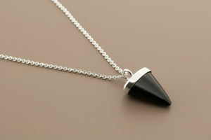Black pyramid-shaped pendant on a silver chain against a gray background