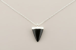 Black triangular pendant on a silver chain against a gray background