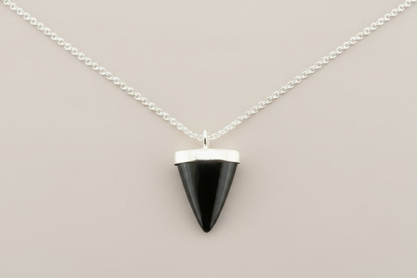 Black triangular pendant on a silver chain against a gray background