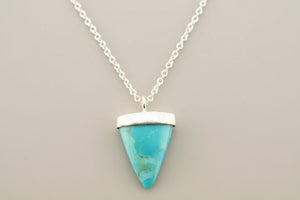 Turquoise triangle pendant necklace on a gray background