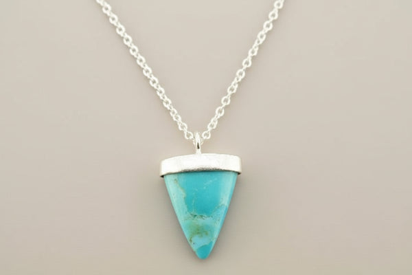 Turquoise triangle pendant necklace on a gray background