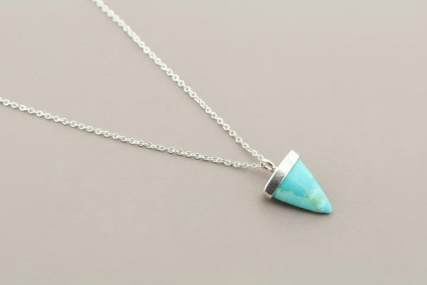 Turquoise triangle pendant necklace on a gray background