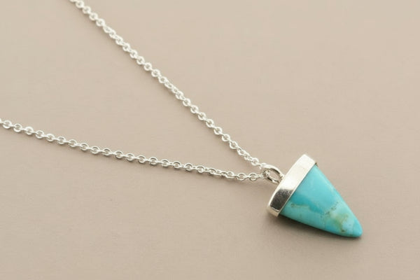 Turquoise cone pendant necklace on a gray background