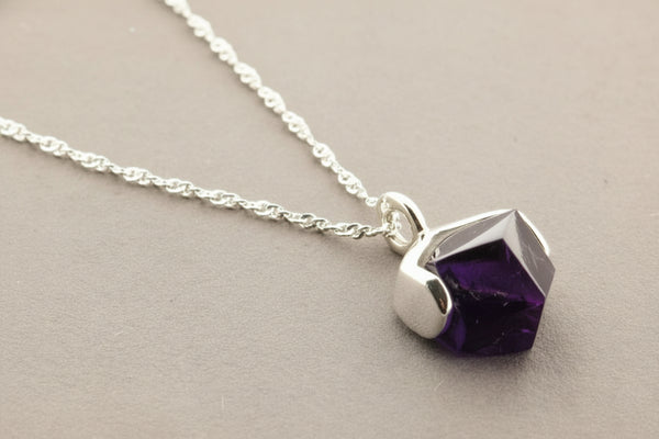Necklace with a purple gemstone pendant on a gray background