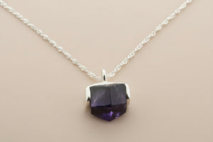 Necklace with a purple faceted pendant on a gray background