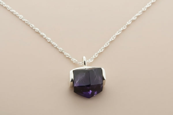 Necklace with a purple faceted pendant on a gray background