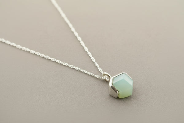 Necklace with a light green hexagonal pendant on a gray background