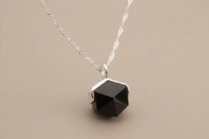 Necklace with a black hexagonal pendant on a gray background