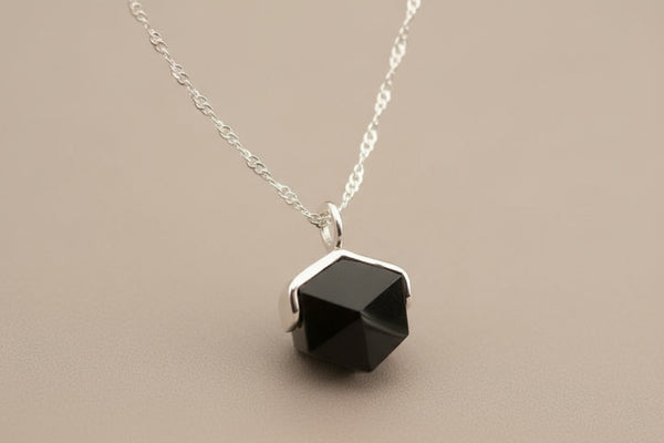 Necklace with a black hexagonal pendant on a gray background