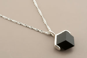 Necklace with a geometric pendant on a gray background