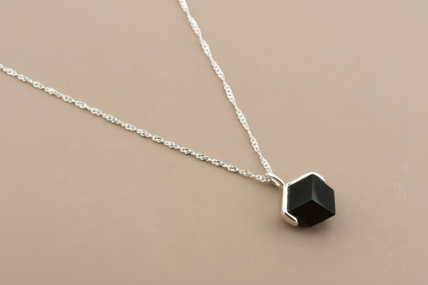 Necklace with a hexagonal black pendant on a gray background