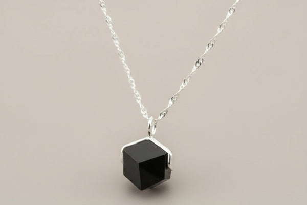 Necklace with a black geometric pendant on a gray background