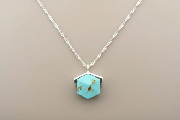 Turquoise hexagonal pendant necklace on a gray background