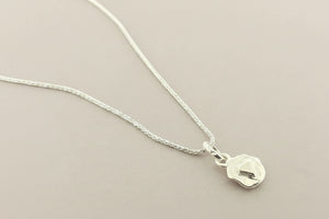 Silver necklace with a small pendant on a gray background