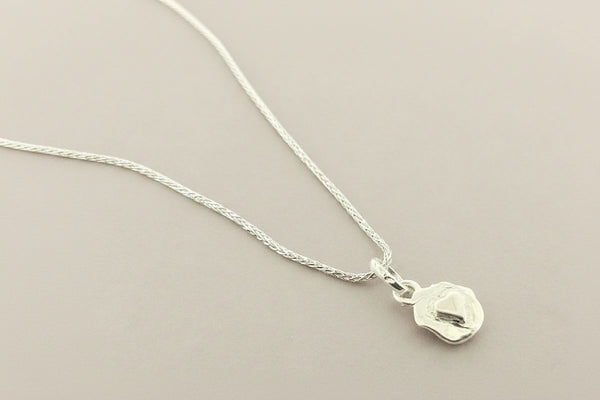 Silver necklace with a small pendant on a gray background