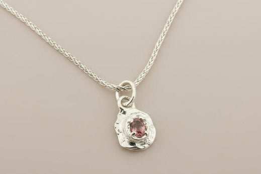 Silver necklace with a pendant on a gray background