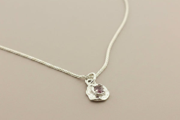 Silver necklace with a pendant on a gray background