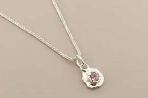 Silver necklace with a small pendant on a gray background