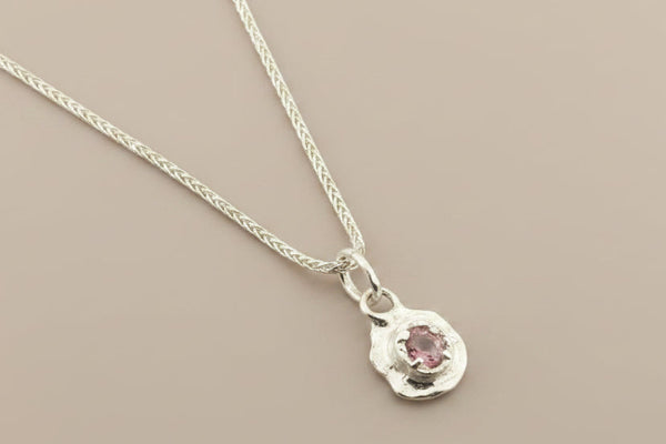 Silver necklace with a small pendant on a gray background