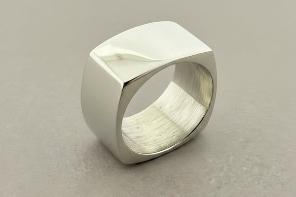 Silver ring with geometric design on a dark gray background