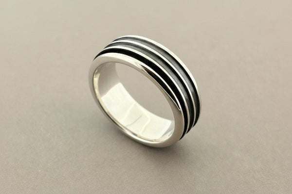 Silver ring with black stripes on a gray background