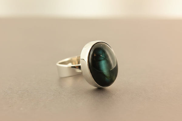 Silver ring with a green cat's-eye gemstone on a gray background