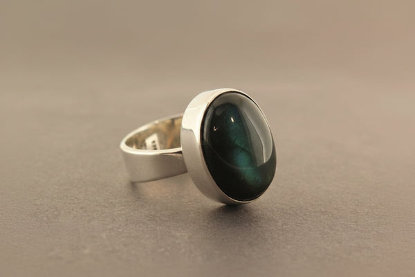 Silver ring with a green stone on a gray surface