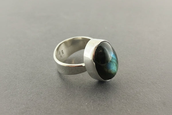 Silver ring with a green gemstone on a gray background