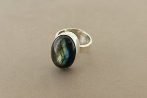 Silver ring with a dark green gemstone on a gray background