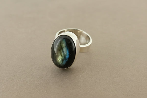 Silver ring with a dark green gemstone on a gray background