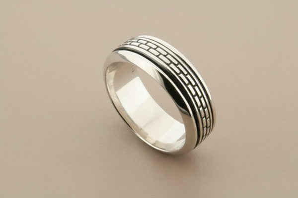 Silver ring with textured design on a gray background