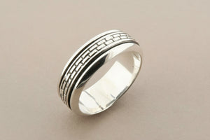 Silver ring with textured design on a gray background