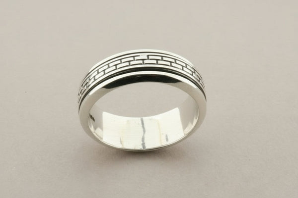 Silver ring with woven design on a gray background
