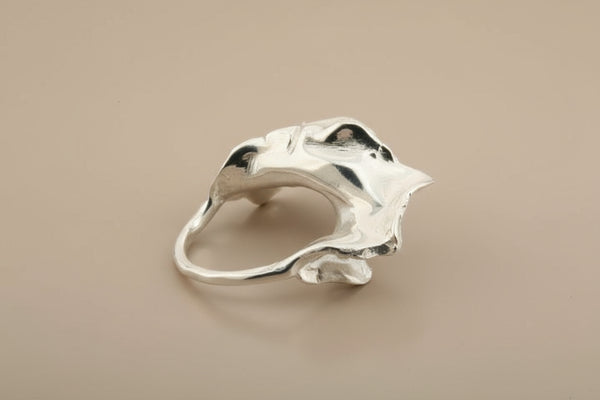 Silver ring with a textured design on a gray background